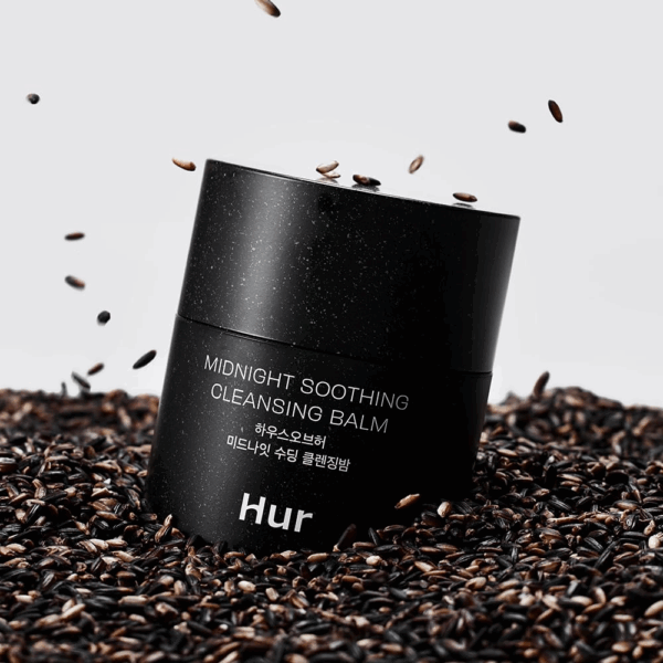 Balm jar resting in a bed of black rice grains with kernels falling around it