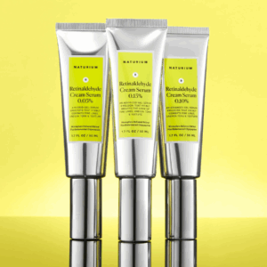 Naturium Retinaldehyde Cream Serum 0.05, 0.10, and 0.15 tubes displayed against yellow background