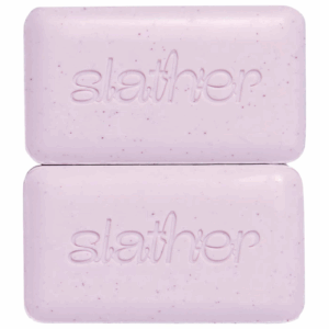 Topicals Slather Exfoliating and Smoothing Body Bar versus Faded Brightening and Cleansing Bar comparison on pink backdrop.