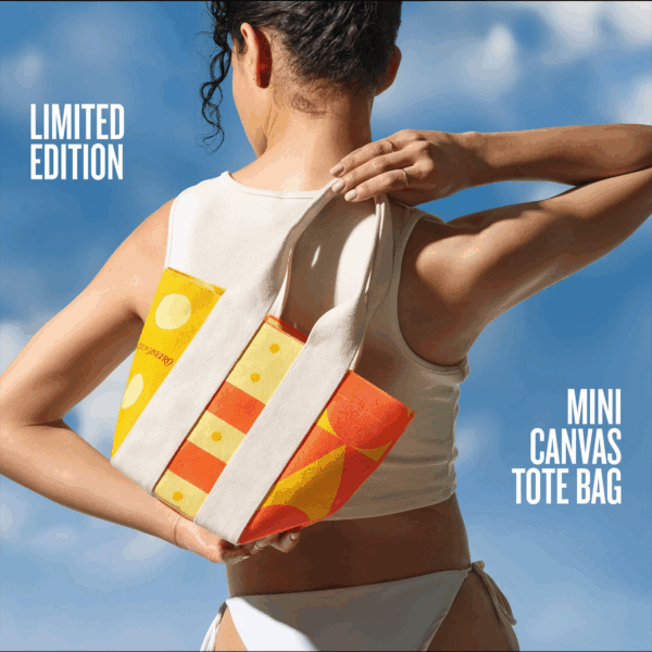 Back view of model carrying Sol de Janeiro limited edition mini canvas tote in orange and yellow
